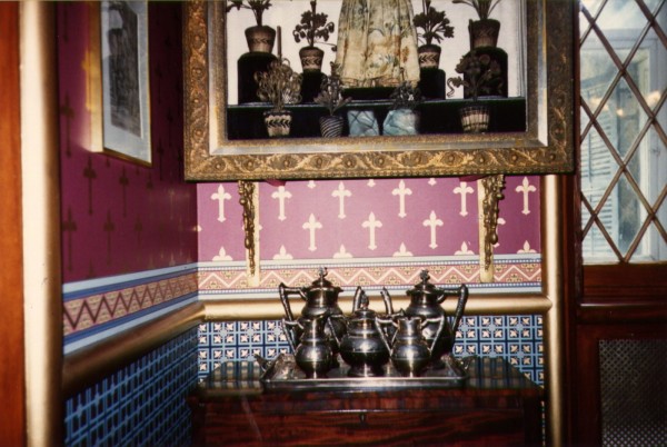 A detail of the interior at Brambleworth shows collected furniture, objects and artworks set off by ornate wallpaper designs and trimmings, and historic architectural features like molding and lozenge-shaped window lattice, 35mm color photo, c. 1980s