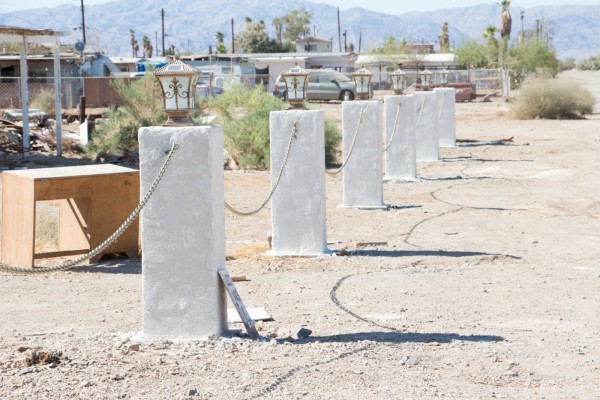 Six concrete pillars with chains connecting them in a desert landscape. 